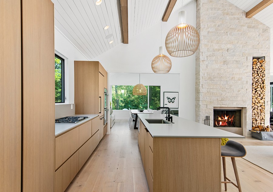 A Bright Open Living Area with a Wood-Toned Kitchen and a Light Stone Fireplace